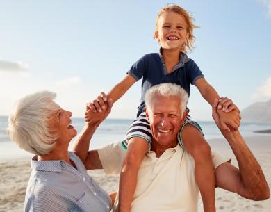 Nonni felici con nipote sulla spiaggia, sorrisi e gioia.