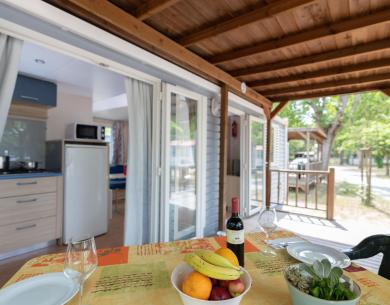 Veranda accogliente con tavolo apparecchiato e cucina visibile.