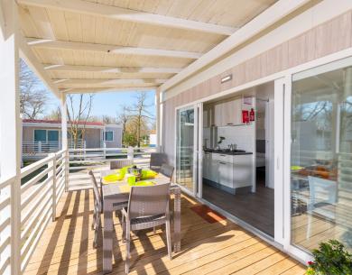 Terrasse mit Tisch und moderner Küche im Mobilheim.