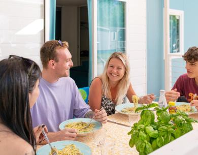 Des amis souriants partagent un repas en plein air, profitant d'une ambiance joyeuse et conviviale.