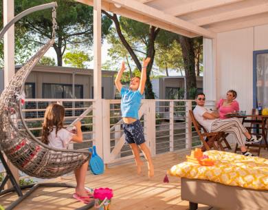Happy family on porch, kids playing, adults relaxing.