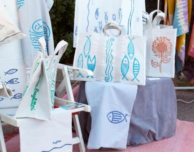 Borse e tessuti colorati con motivi di pesci e fiori in un ambiente vivace.