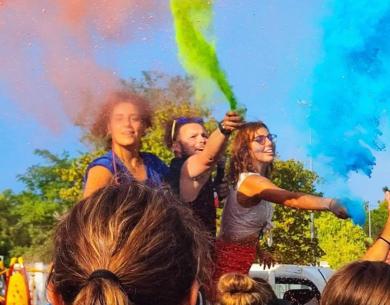 Giovani festeggiano con colori vivaci, sprigionando gioia e libertà all'aperto.