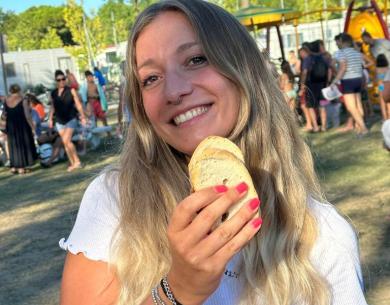 Ragazza sorridente con pane in mano, festa all'aperto, atmosfera gioiosa.