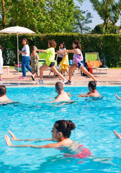 Menschen im Pool machen Übungen, andere gehen und entspannen sich.