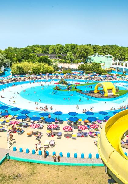 Parco acquatico vivace con scivoli, ombrelloni colorati e persone che si divertono.