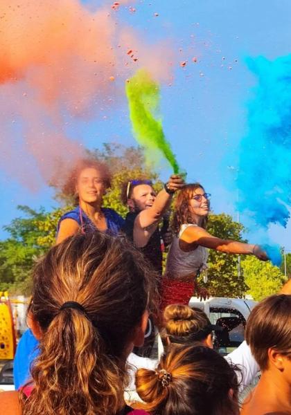 Giovani festeggiano con colori vivaci, sprigionando gioia e libertà all'aperto.
