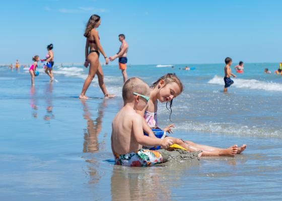 Kinder spielen am Strand, während andere das Meer genießen.