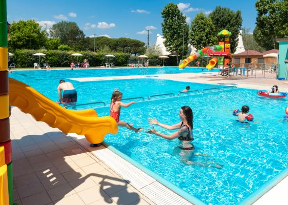 Kinder spielen im Pool mit bunten Rutschen und Eltern, die aufpassen.