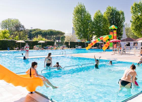 Piscina all'aperto con scivolo e persone che si divertono.