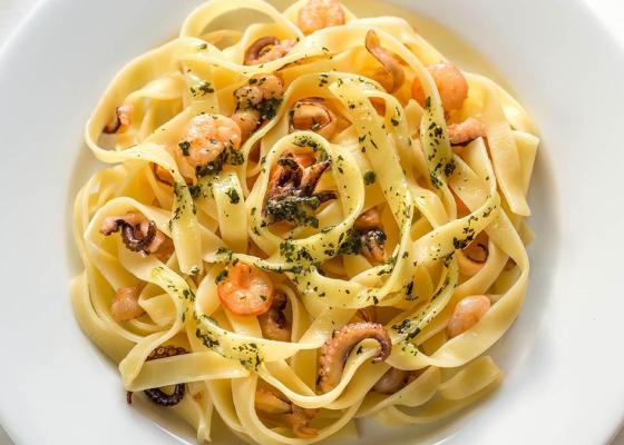 Tagliatelle con gamberetti e polpo, condite con erbe aromatiche.