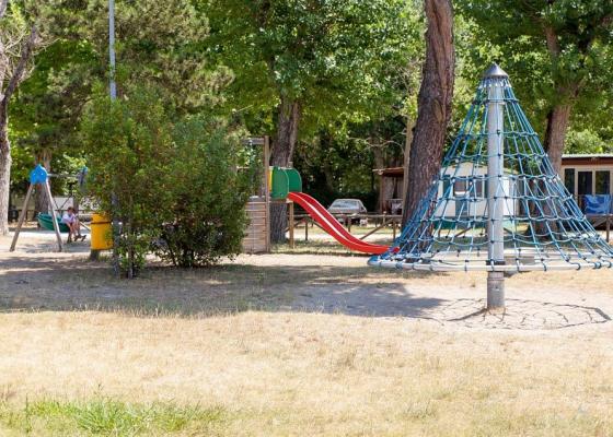Parco giochi con scivolo rosso e struttura di arrampicata a rete.