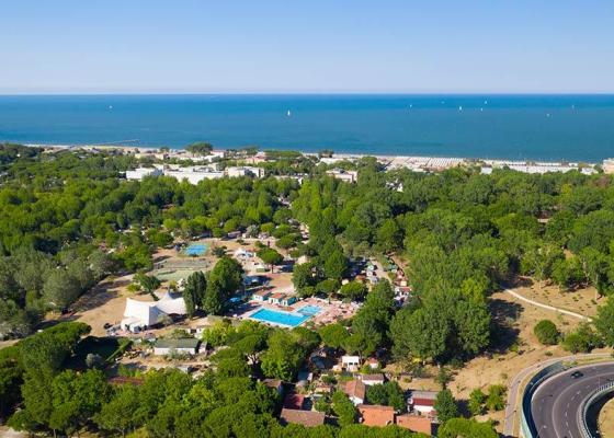 Vista aerea di un campeggio vicino al mare con piscina e vegetazione.