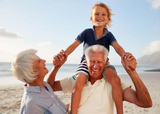 Nonni felici con nipote sulla spiaggia, sorrisi e gioia.