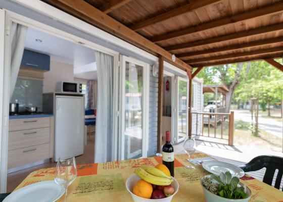 Veranda accogliente con tavolo apparecchiato e cucina visibile.