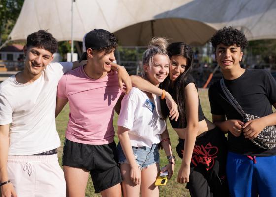Gruppo di amici sorridenti all'aperto in una giornata di sole.