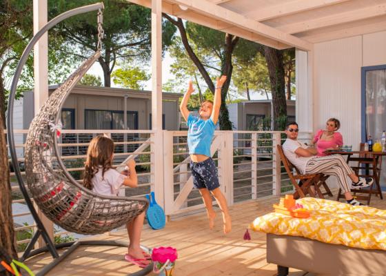 Happy family on porch, kids playing, adults relaxing.