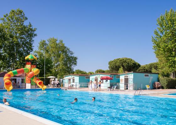 Piscina soleggiata, scivolo colorato, risate e relax estivo all'aperto.