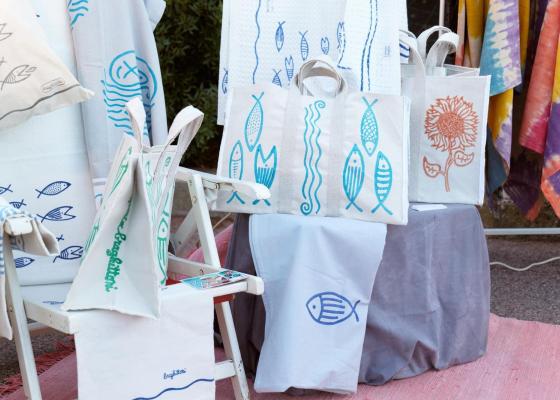 Borse e tessuti colorati con motivi di pesci e fiori in un ambiente vivace.