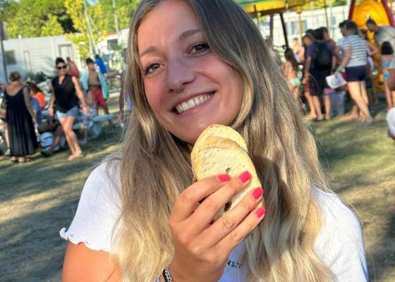Ragazza sorridente con pane in mano, festa all'aperto, atmosfera gioiosa.