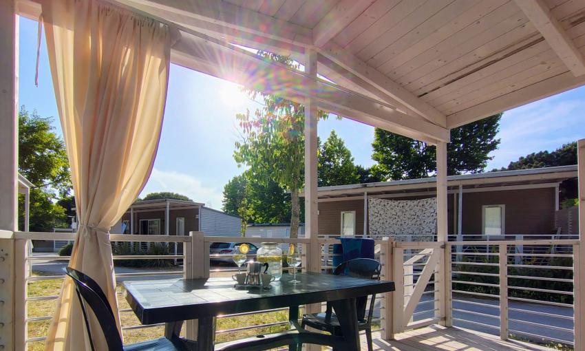 Veranda soleggiata, tavolo apparecchiato, atmosfera tranquilla e rilassante.