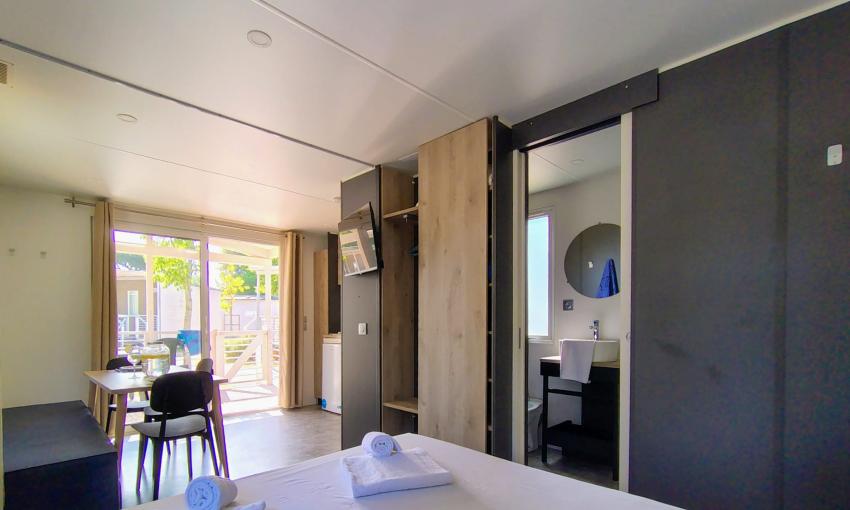 Moderno appartamento luminoso con letto matrimoniale, bagno e vista su veranda soleggiata.
