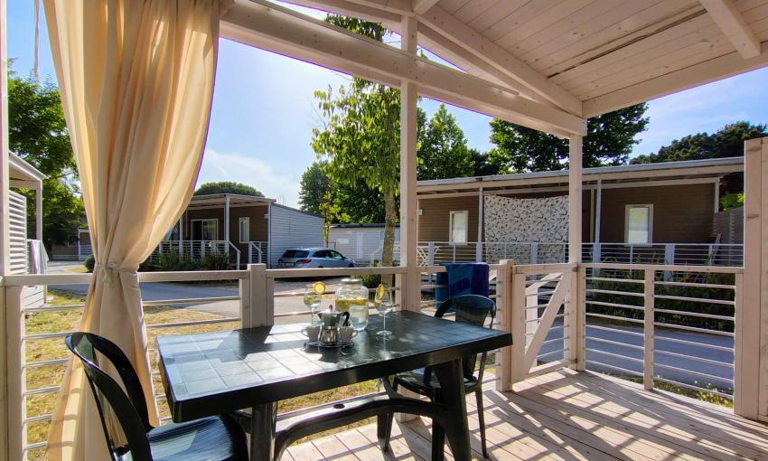 Veranda soleggiata, tavolo apparecchiato, atmosfera rilassante in un villaggio vacanze.